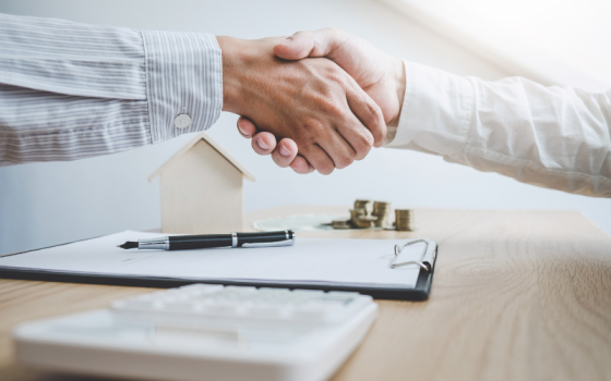 Handshake over desk with clipboard and pen